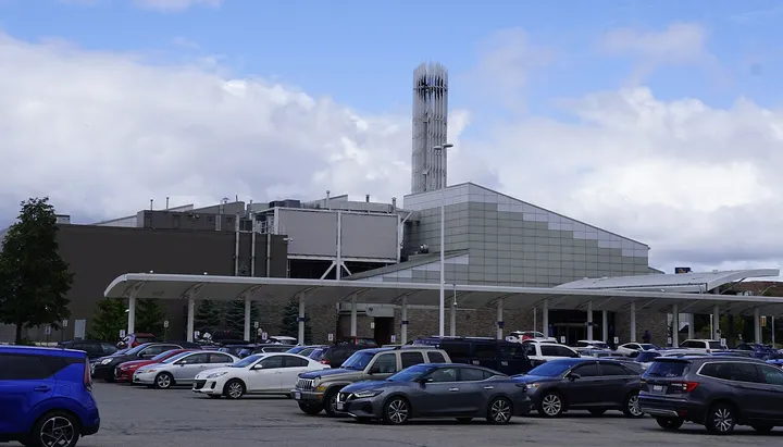 The casino building on Icomm Drive by day: a low building with a long white entrance canopy and a tall tower, cars in the parking lot.